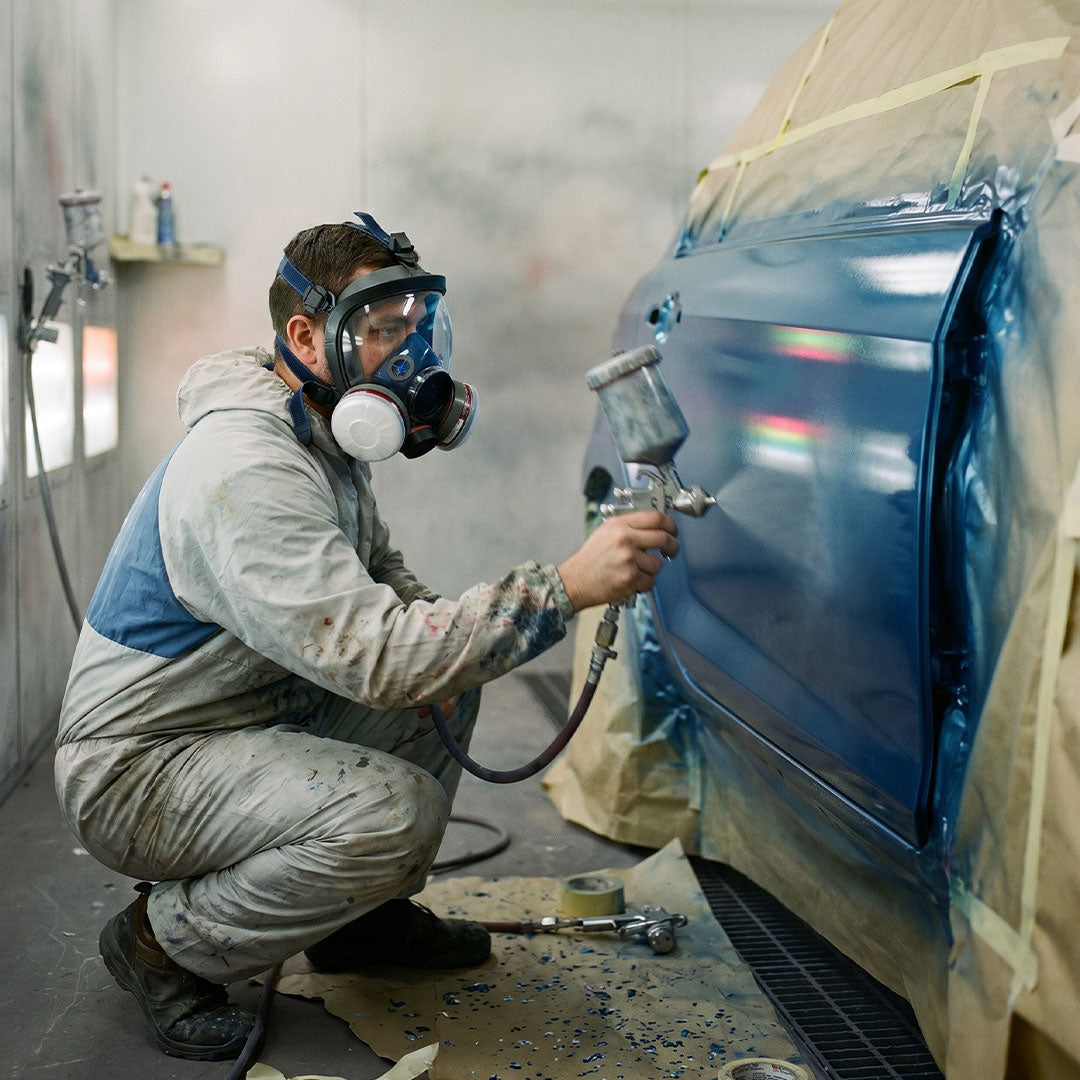 Person spray painting a car in a controlled environment